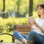 공원 벤치에 앉아 편안하게 책을 읽는 한국인 여성의 사실적인 모습. 스마트폰 대신 책을 들고 있으며, 배경에는 흐릿하게 스마트폰 형태가 보여 디지털 디톡스를 상징합니다.